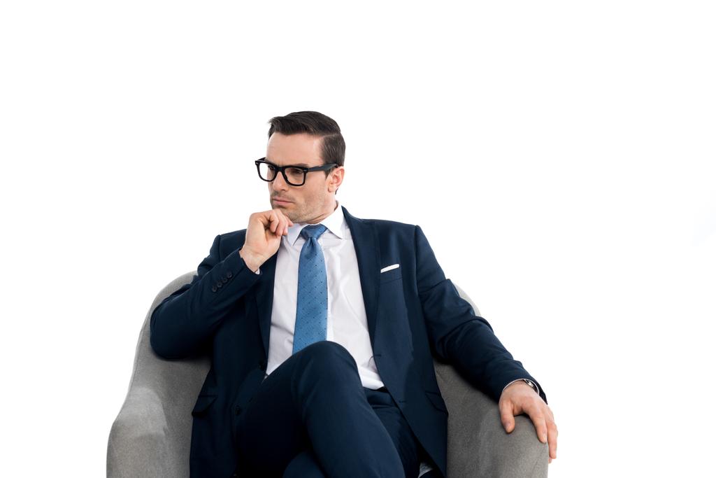 sérieux homme d'affaires d'âge moyen dans les lunettes et les vêtements formels assis dans le fauteuil et regardant loin isolé sur blanc
  - Photo, image