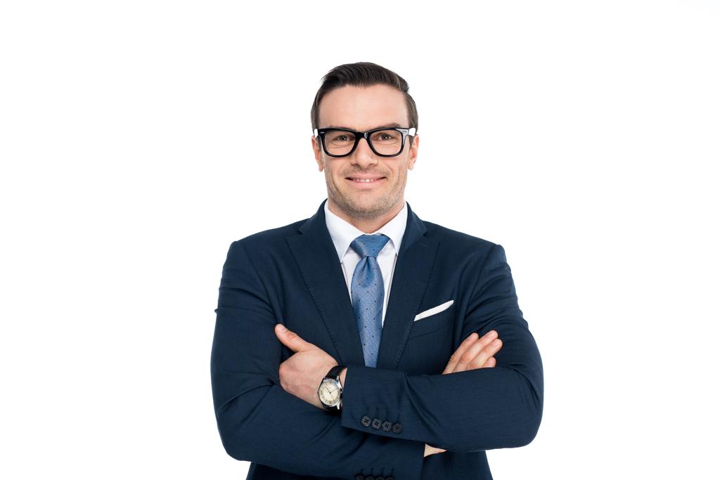 confident businessman in eyeglasses standing with crossed arms and smiling at camera isolated on white  - Photo, Image