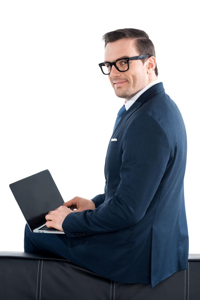homem de negócios em terno e óculos usando laptop com tela em branco e olhando para a câmera isolada no branco
 - Foto, Imagem