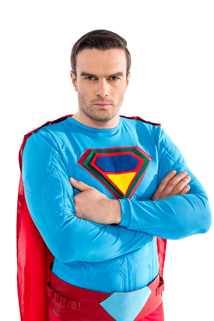 selbstbewusster gutaussehender Superman, der mit verschränkten Armen steht und isoliert auf weiß in die Kamera schaut  - Foto, Bild