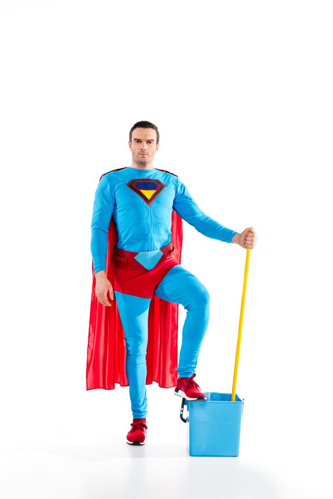 confident man in superhero costume standing with mop and bucket, looking at camera on white - Photo, Image