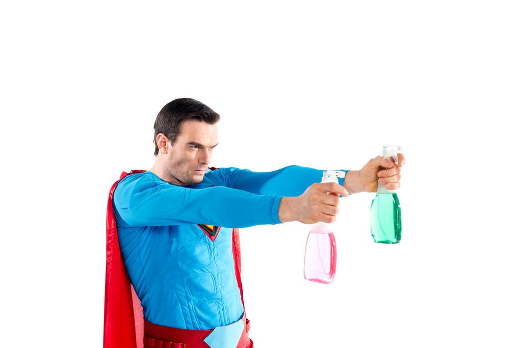 Selbstbewusster Superheld hält Plastiksprühflaschen mit Reinigungsflüssigkeit in der Hand und schaut isoliert auf weißem Grund weg    - Foto, Bild