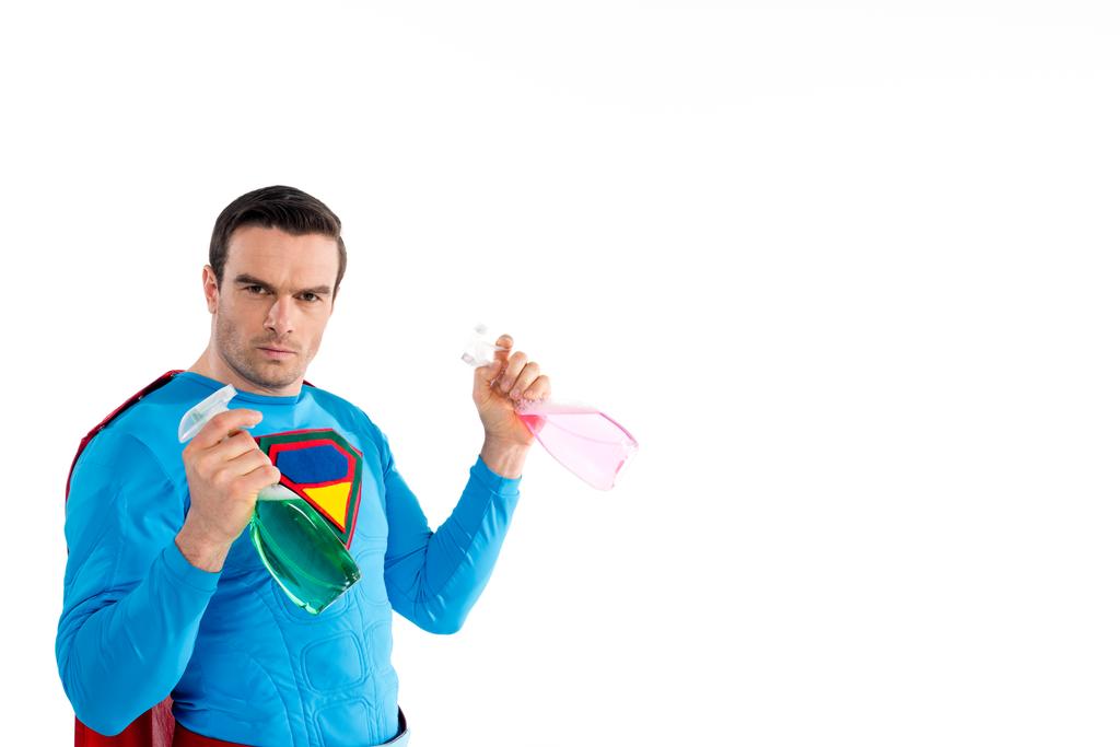 superhéroe confiado sosteniendo botellas de plástico con líquido de limpieza y mirando a la cámara aislada en blanco
   - Foto, imagen