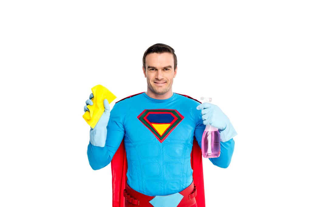 uśmiechnięty mężczyzna superbohatera, trzymając butelkę rag i spray z detergentu na białym tle - Zdjęcie, obraz