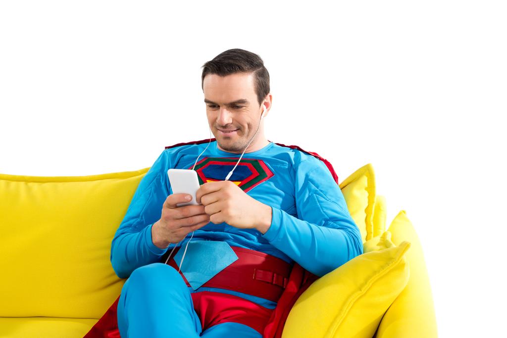 hymyilevä supermies kuulokkeissa istuu sohvalla ja käyttää älypuhelinta eristetty valkoinen
 - Valokuva, kuva