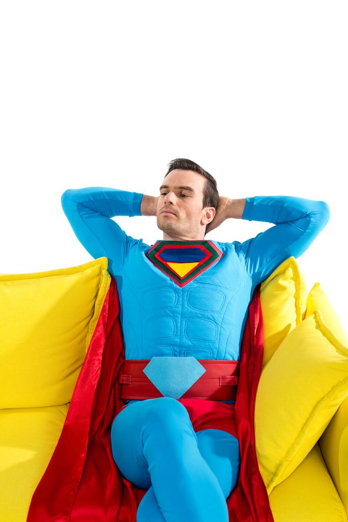 schöner männlicher Superheld ruht auf gelbem Sofa isoliert auf weißem - Foto, Bild