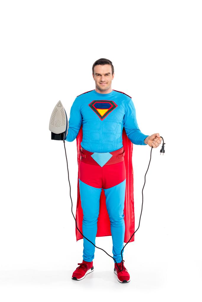 Lächelnder männlicher Superheld hält Eisen und Stecker isoliert auf weiß - Foto, Bild