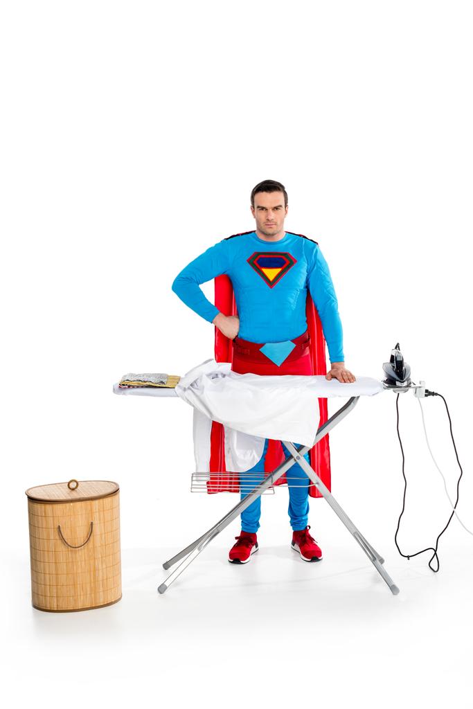 guapo superman planchando ropa y mirando a la cámara en blanco
 - Foto, Imagen