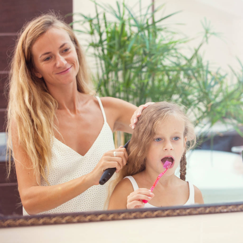 Mother and daughter brushing their teeth in the bathroom. Family at the morning - Photo, Image