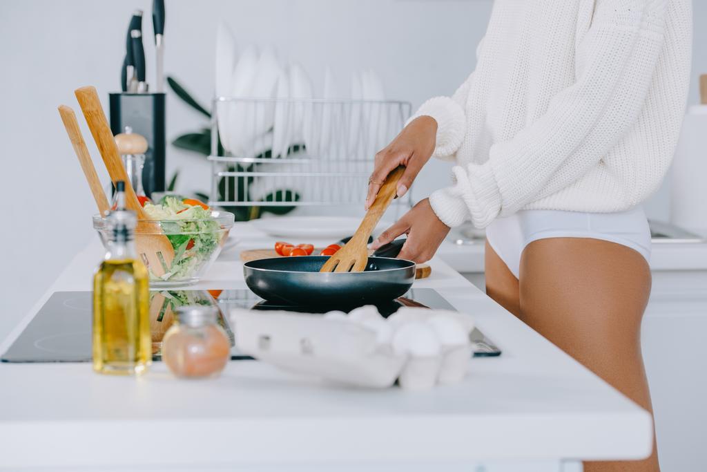 Schnappschuss von Frau, die in Küche Frühstück mit Pfanne zubereitet - Foto, Bild