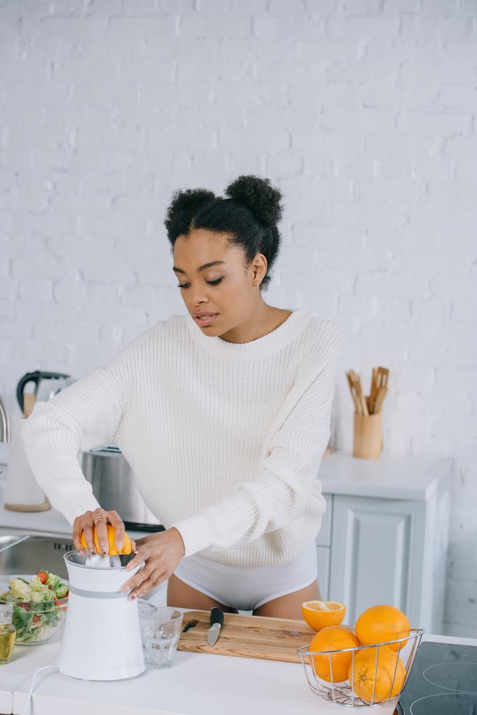 美しい若い女性のキッチンで新鮮なオレンジ ジュースを絞る - 写真・画像