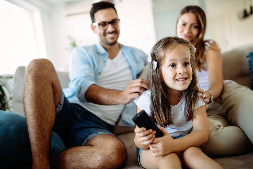 Famiglia felice divertirsi guardando la tv a casa
 - Foto, immagini