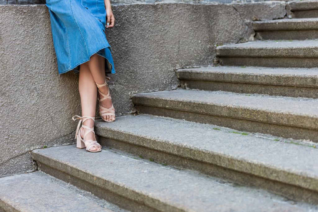 обрезанный снимок женщины в джинсовой юбке и стильные туфли, стоящие на ступеньках
 - Фото, изображение