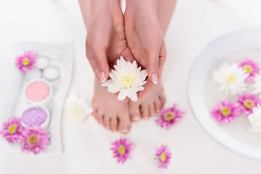 gedeeltelijke weergave van barefoot vrouw bedrijf bloem op de procedure in de beauty salon  - Foto, afbeelding