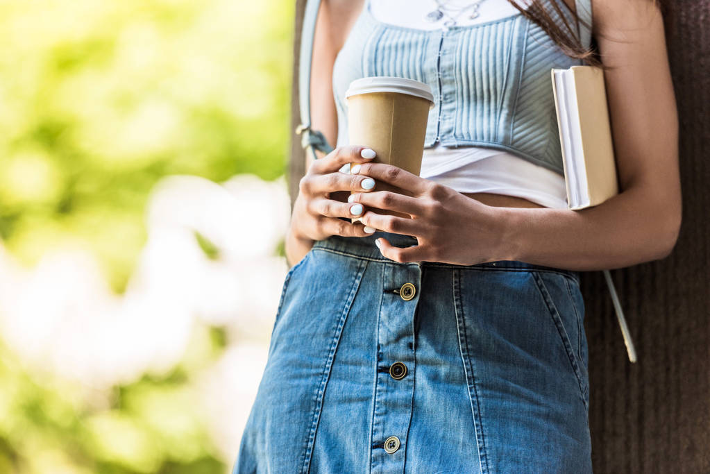 частичный вид женщины с книгой и кофе, чтобы выйти на улицу
 - Фото, изображение