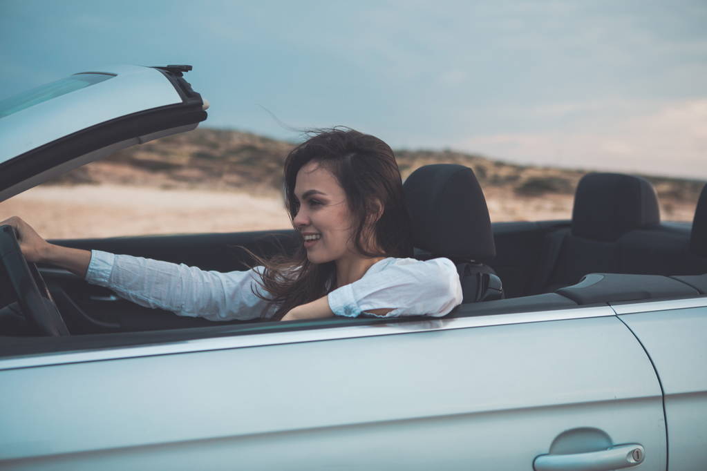 Happy young woman is driving a convertible car  - Photo, Image