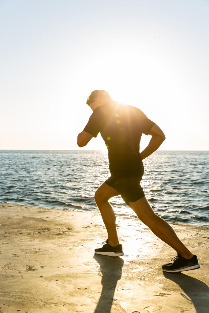 ενήλικα αθλητή τζόκινγκ στην παραλία μπροστά από την Ανατολή του ηλίου - Φωτογραφία, εικόνα