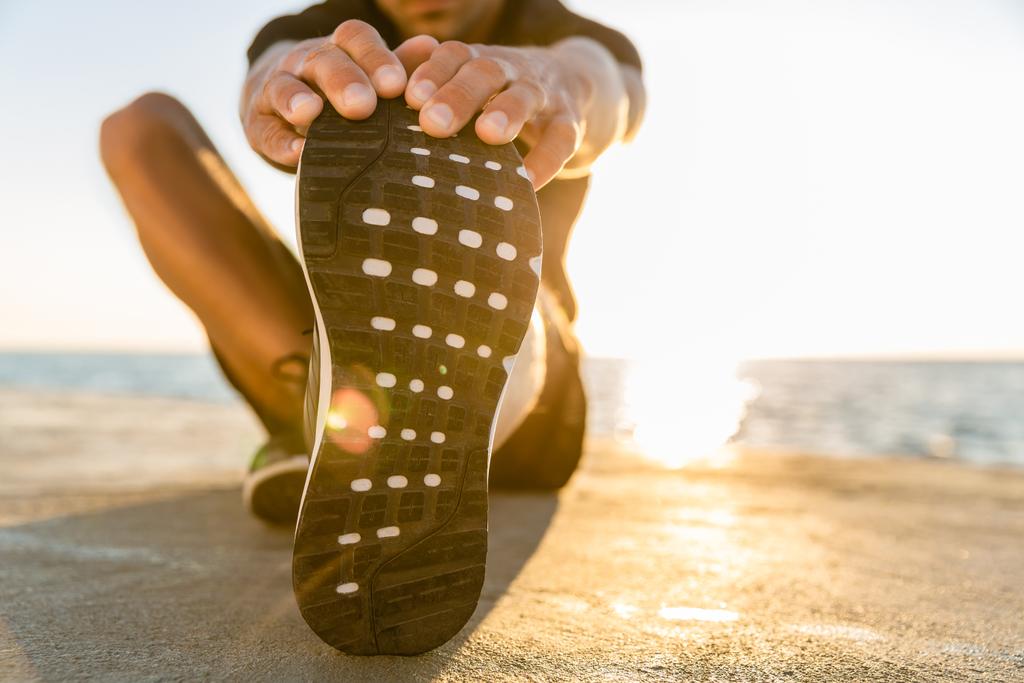 apuesto deportista adulto estiramiento pierna en la orilla del mar
 - Foto, Imagen