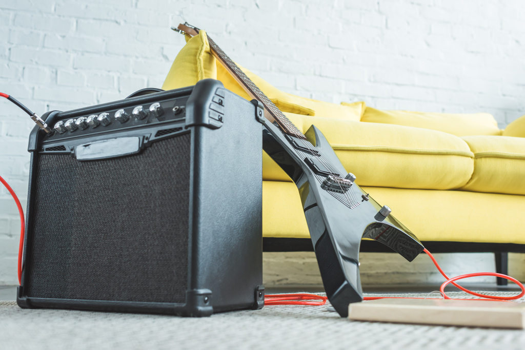 Elektrická kytara a hlasitý reproduktor, stojící na podlaze pohovka - Fotografie, Obrázek
