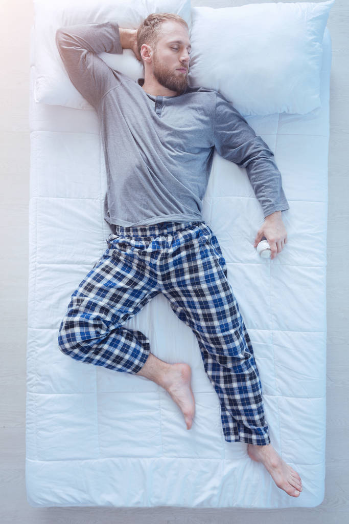 Młody człowiek, Śpiące w łóżku z baseball w ręku - Zdjęcie, obraz