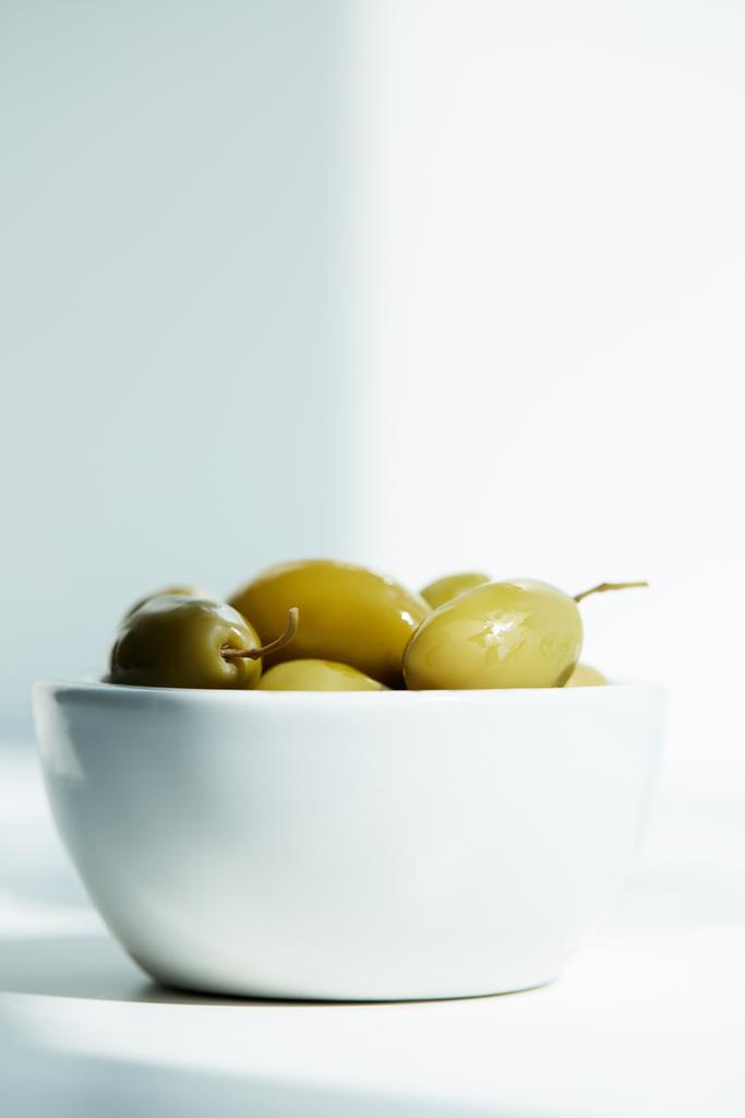 Schüssel mit grünen Oliven auf weißem Tisch  - Foto, Bild