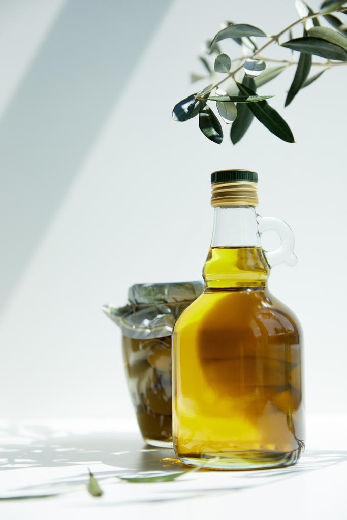 μπουκάλι αρωματικό ελαιόλαδο, υποκατάστημα και βάζο με πράσινες ελιές σε πίνακα - Φωτογραφία, εικόνα