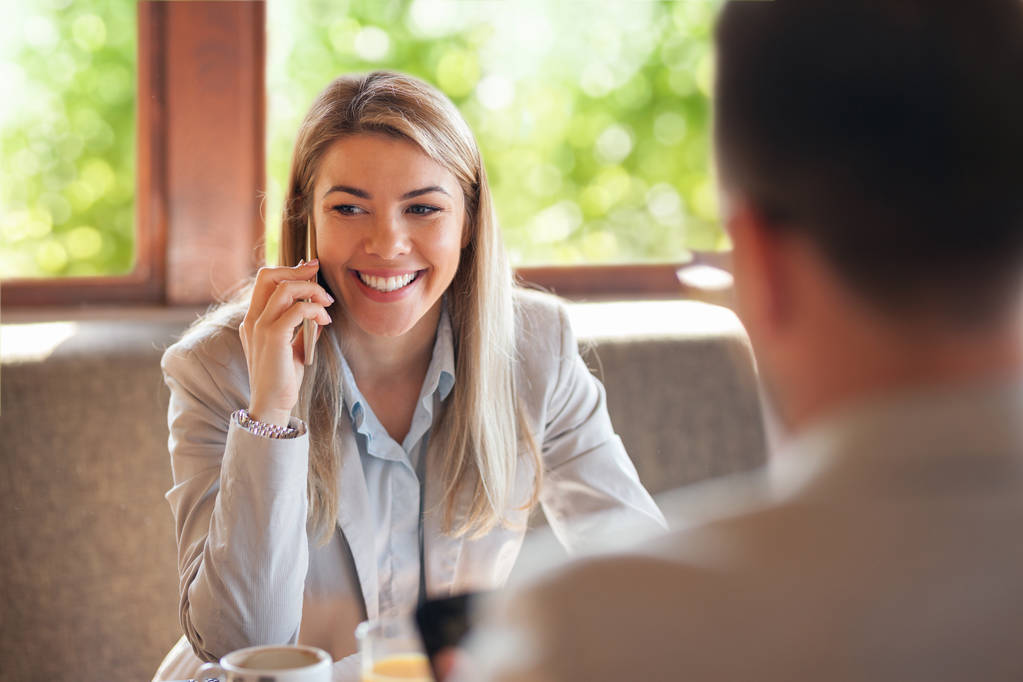 Retrato de bela mulher de negócios telefonando enquanto reunião não convencional
 - Foto, Imagem