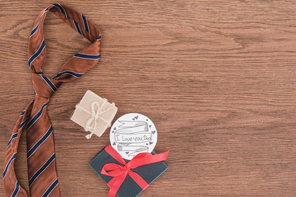 Draufsicht auf Krawatte mit Geschenken und Glückwunsch zum Vatertag auf Holzfläche - Foto, Bild