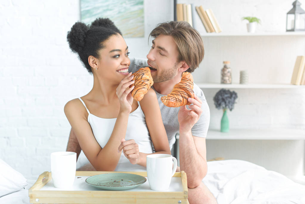 retrato de jovem casal multirracial tomando café da manhã na cama em casa
 - Foto, Imagem
