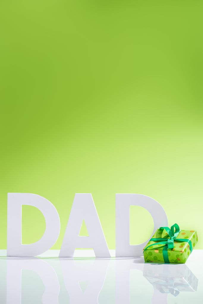 caja de regalo verde frente a la inscripción de papá hecha de letras blancas en concepto de día de padres felices verde
 - Foto, imagen