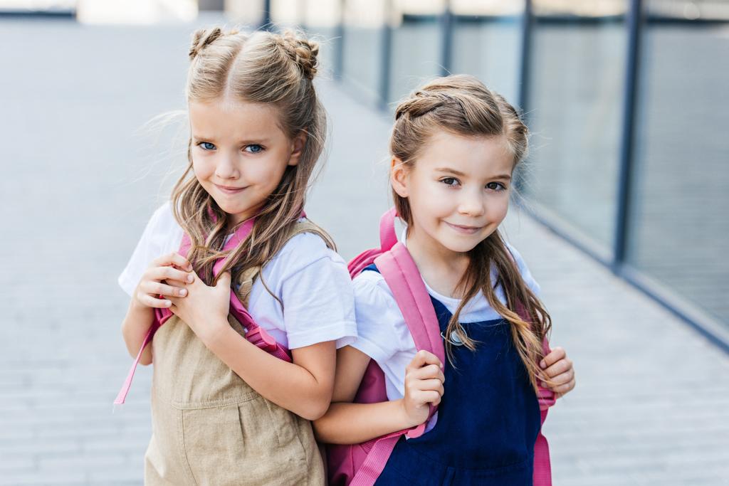 mosolygó kis iskolás, rózsaszín hátizsákok utca keresi kamera - Fotó, kép