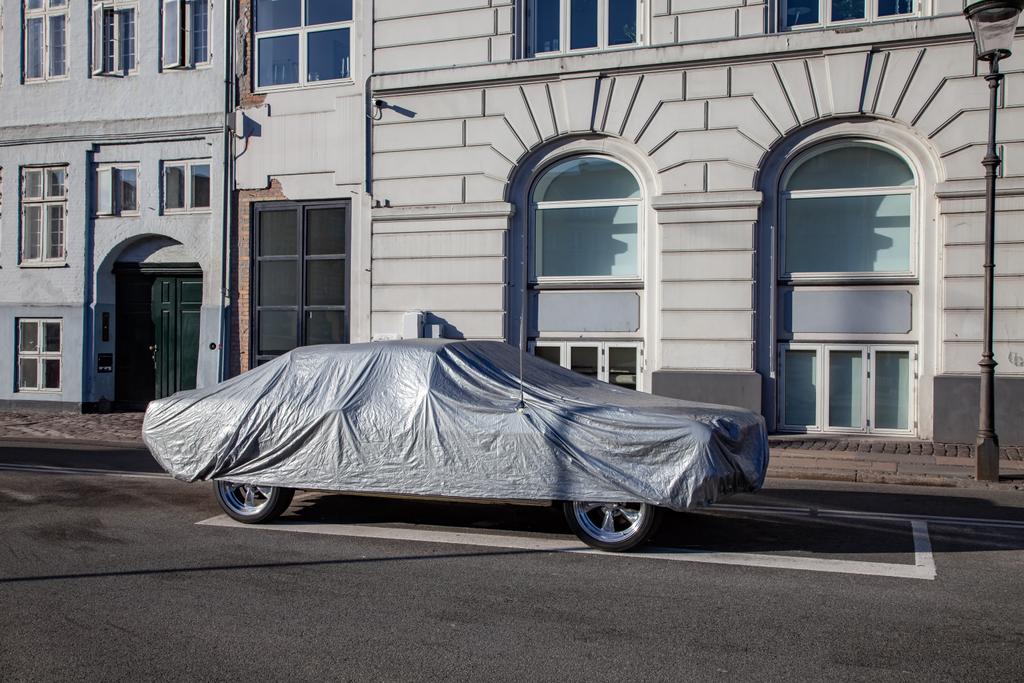 geparkeerde auto bedekt met tent op lege straat met historische gebouwen in Kopenhagen, Denemarken - Foto, afbeelding