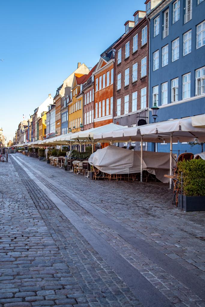 Bruk i parasole w ulicznej kawiarni w pobliżu piękne kolorowe domy w Kopenhadze, Dania - Zdjęcie, obraz