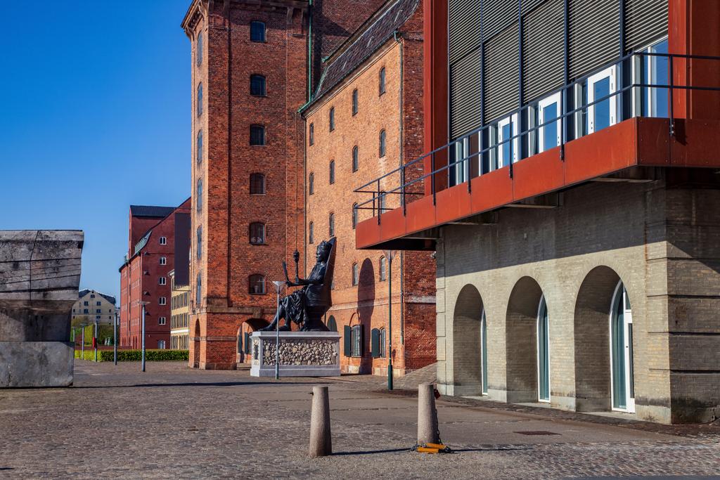 estátua histórica no pavimento perto de edifícios na rua vazia em copenhagen, denmark
 - Foto, Imagem