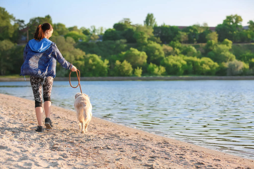 Nuori nainen koiransa kanssa rannalla. Lemmikkieläinten hoito
 - Valokuva, kuva