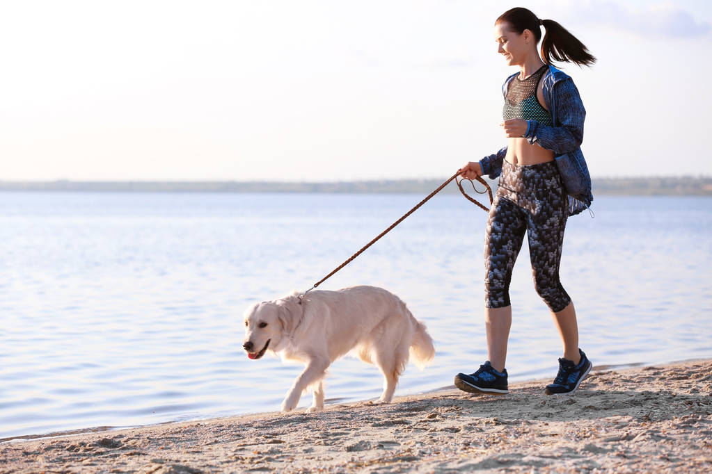Giovane donna con il suo cane insieme sulla spiaggia. Cura degli animali
 - Foto, immagini