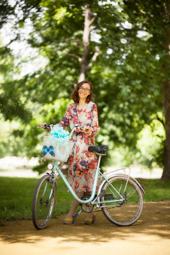 девушка с винтажным велосипедом на дороге в парке
 - Фото, изображение