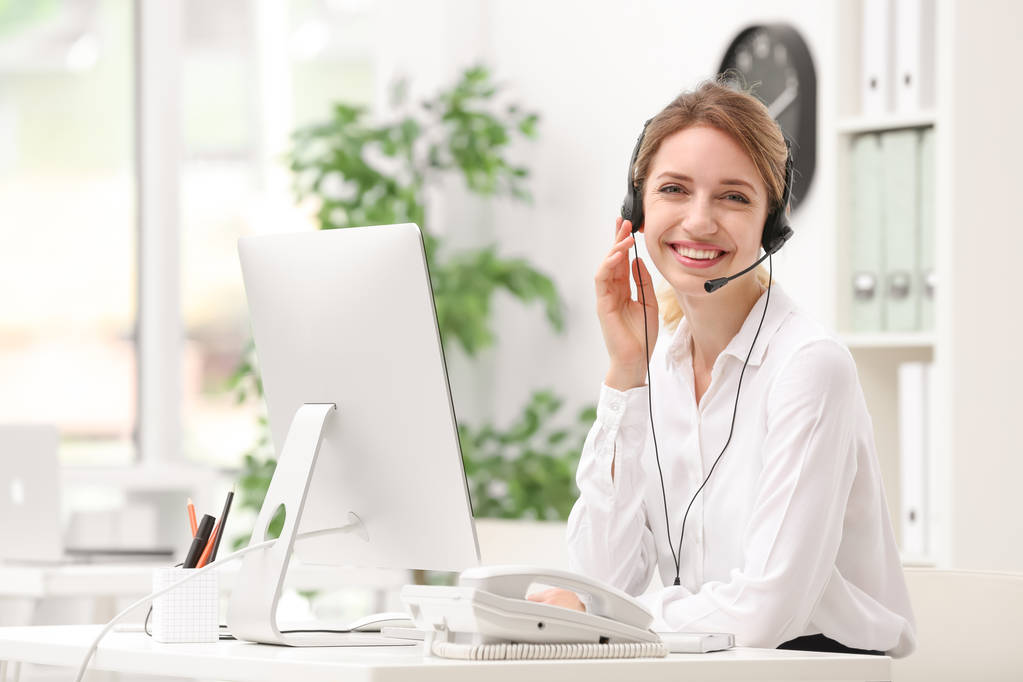 Recepcionista femenina con auriculares en escritorio en la oficina
 - Foto, Imagen