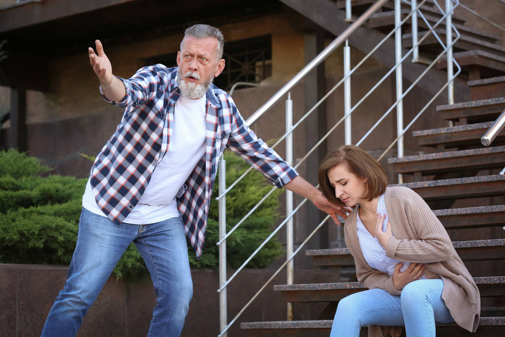 Hombre ayudando a la mujer madura que tiene un ataque al corazón en las escaleras, al aire libre
 - Foto, Imagen