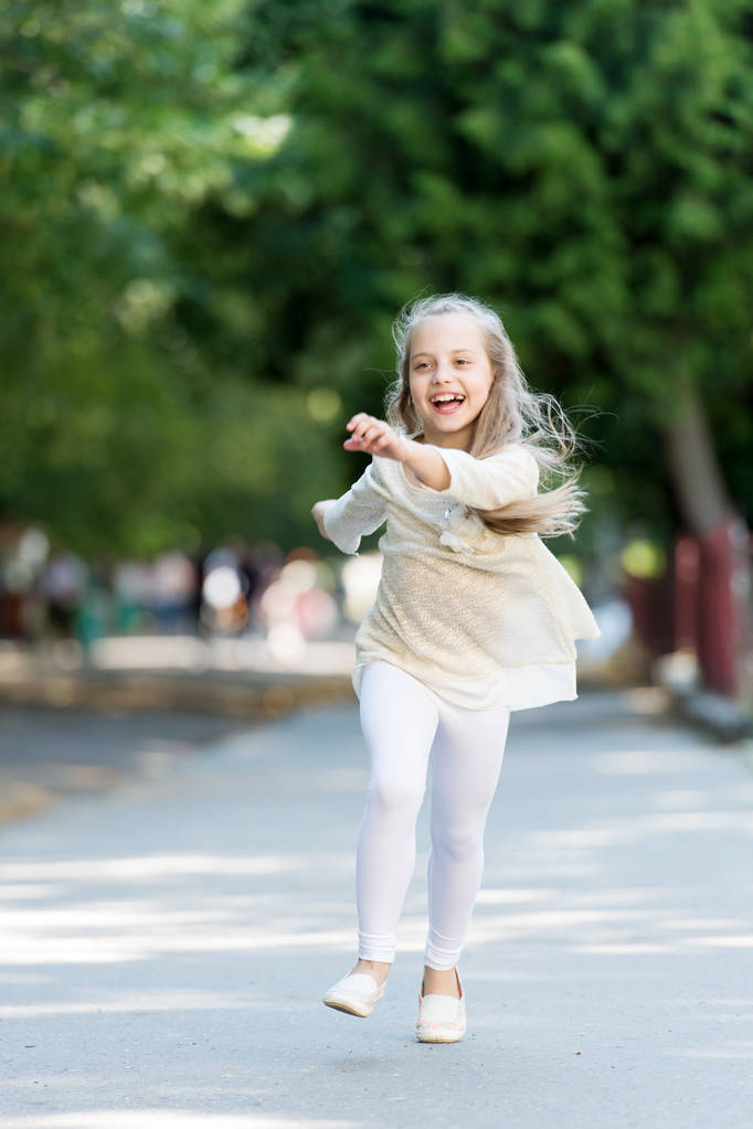 Dziecko, szczęśliwy i radosny spacer w parku. Koncepcja dzieciństwa. Dziecko dziewczynka z wesoły wyrażenie biegać lub chodzić na międzynarodowych dzieci dzień. Dziewczynka na szczęśliwy twarz uśmiechający się idzie, natura na tle - Zdjęcie, obraz