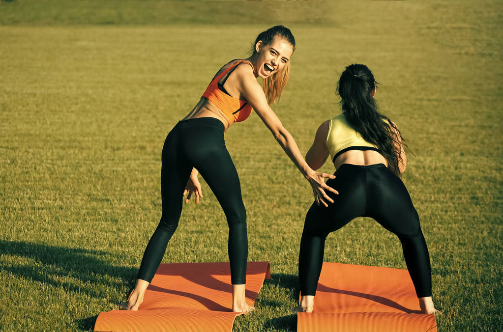 Kuntoiluvitsejä. Energia naiset tekevät urheilullinen harjoituksia vihreä ruoho
 - Valokuva, kuva