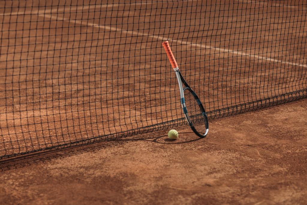 τένις μπάλα και τη ρακέτα που ακουμπά στο δίχτυ - Φωτογραφία, εικόνα