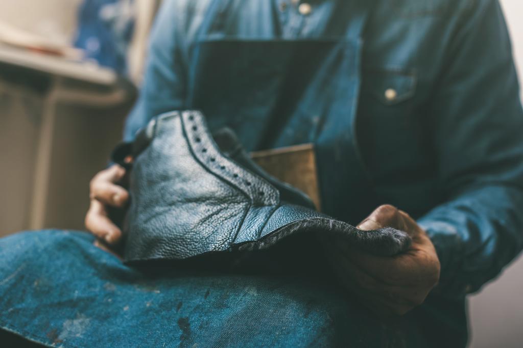 cropped shot of cobbler holding unfinished leather shoe at workshop - Photo, Image