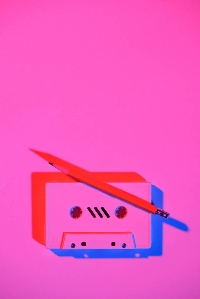 toned pink picture of retro audio cassette and pencil on tabletop - Photo, Image