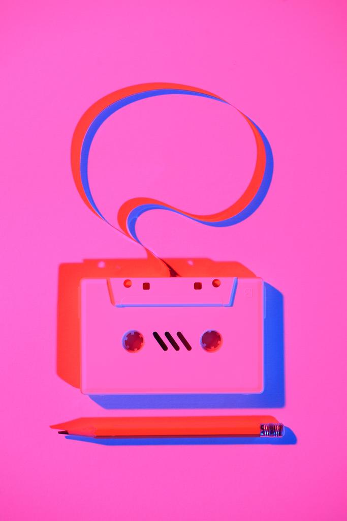 getöntes rosafarbenes Bild von Bleistift und Retro-Audiokassette mit Sprechblase - Foto, Bild