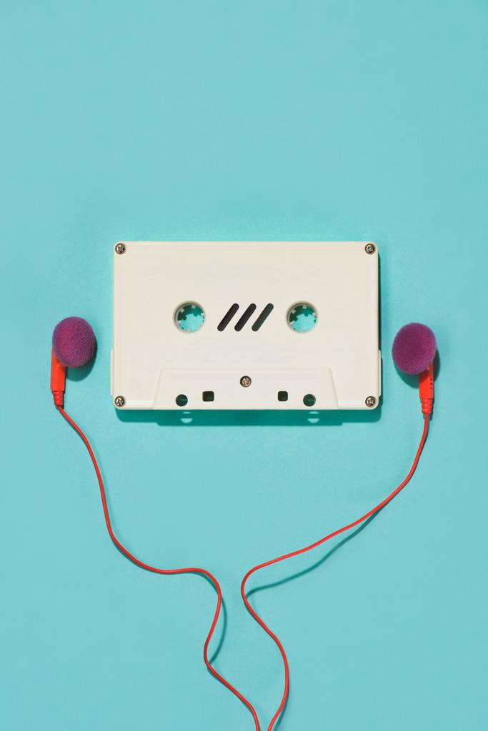 vlakke leggen met wit retro audio cassette en oortelefoons geïsoleerd op blauw - Foto, afbeelding