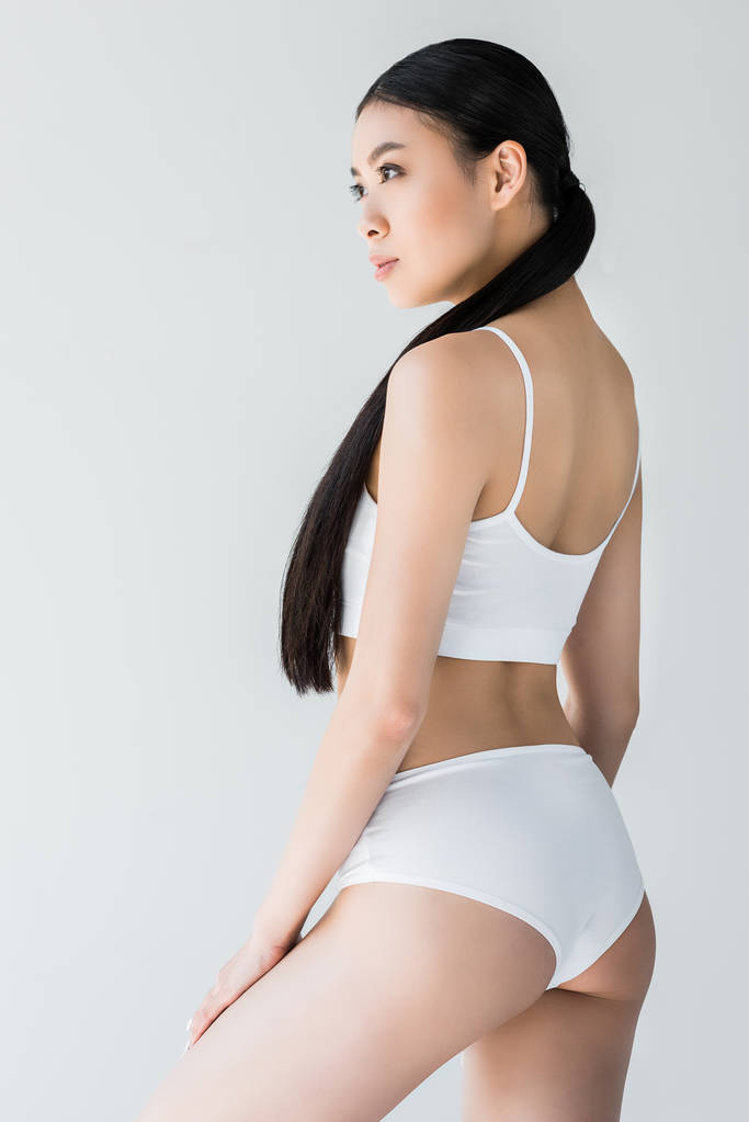vue latérale de attrayant asiatique femme en lingerie blanche isolé sur fond gris
  - Photo, image