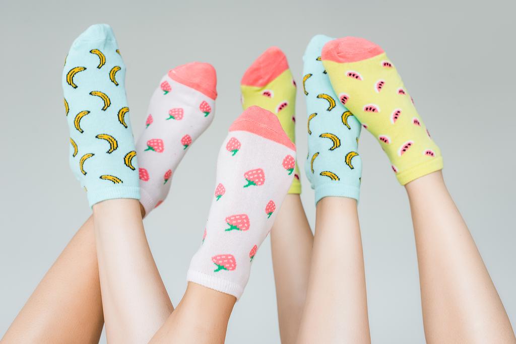vue partielle des pieds féminins en chaussettes fruitées colorées, isolées sur gris
 - Photo, image