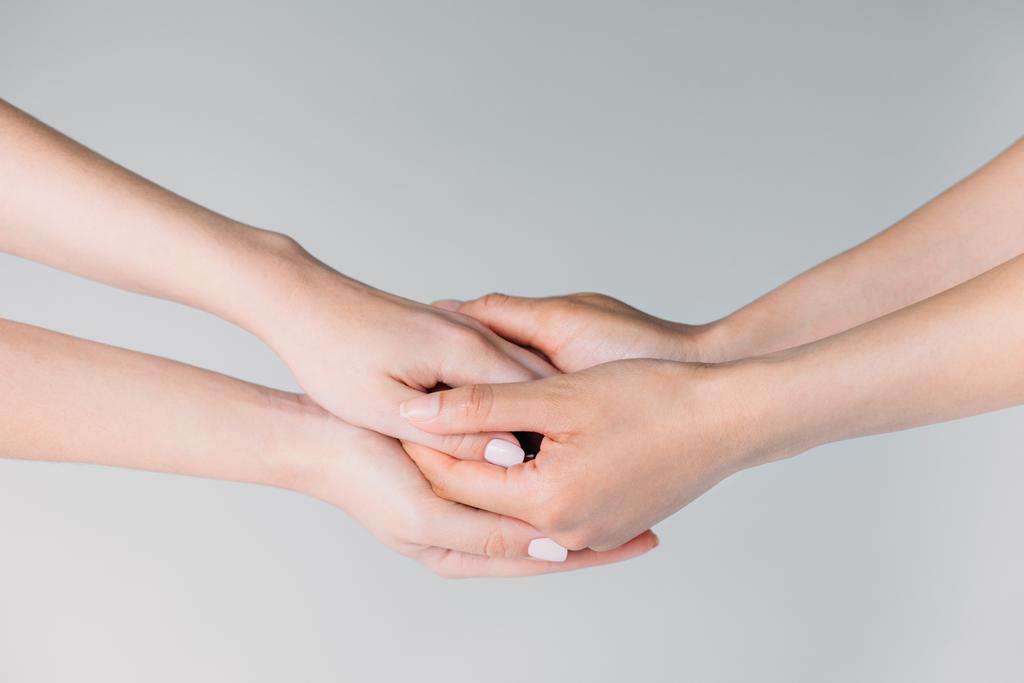 частичный взгляд на подруг, держащихся за руки, изолированных на сером
 - Фото, изображение