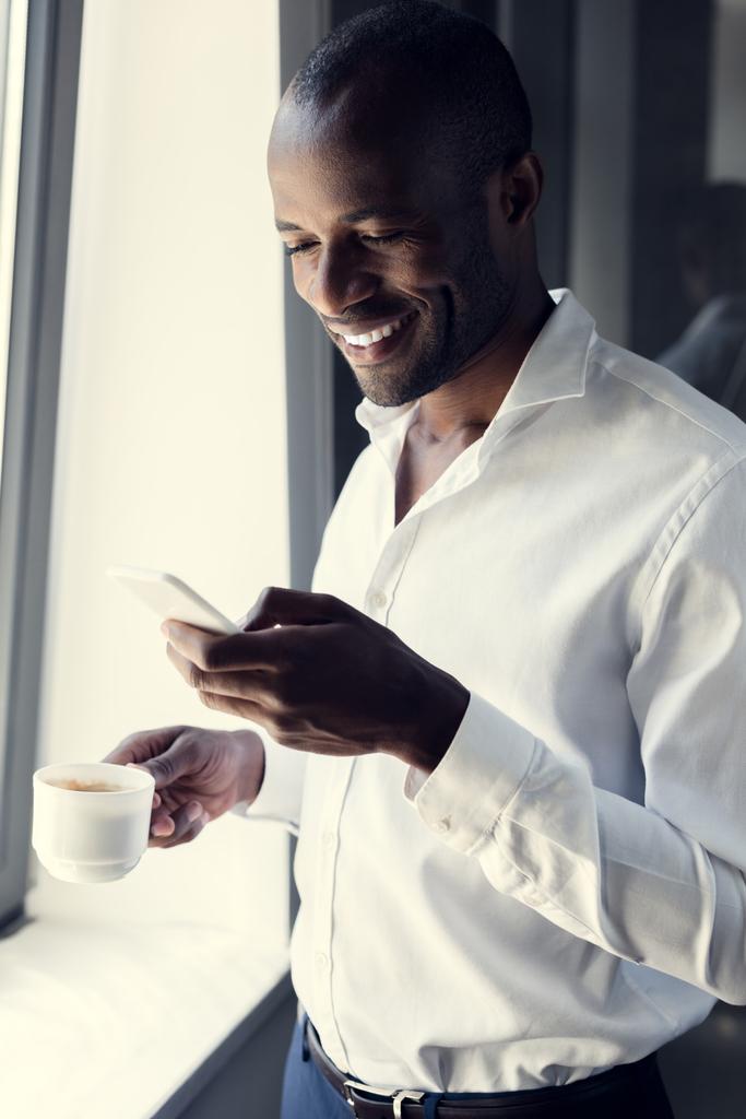 giovane uomo d'affari sorridente in camicia bianca utilizzando lo smartphone durante la pausa caffè
 - Foto, immagini